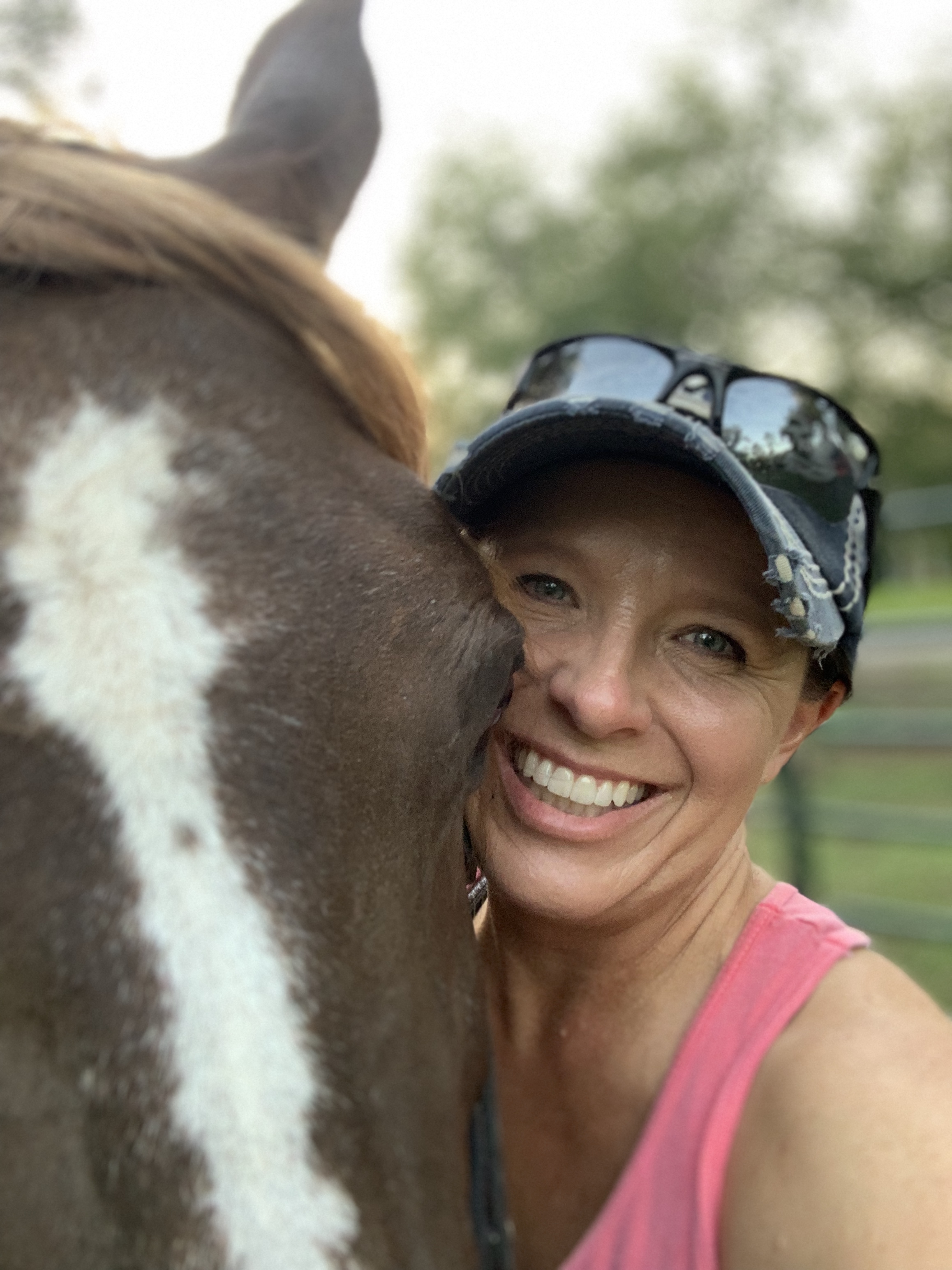 Janet with a big smile standing next to a horse white blaze